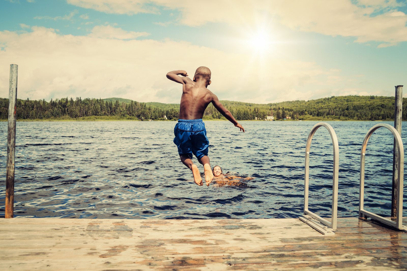 Kid jumping off dock into the lake